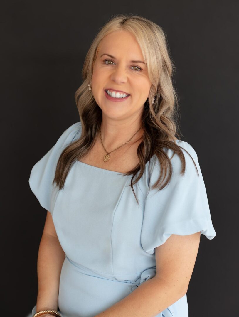 Smiling woman in a light blue dress.