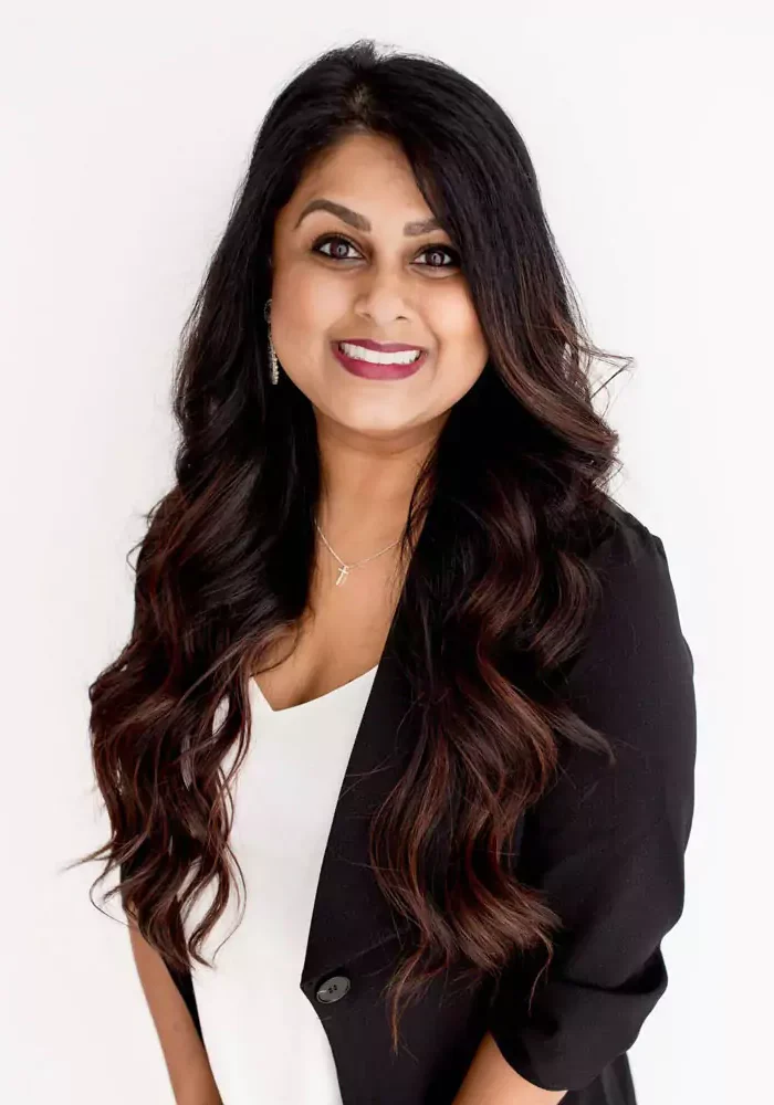 Smiling woman with long dark hair wearing a black blazer.