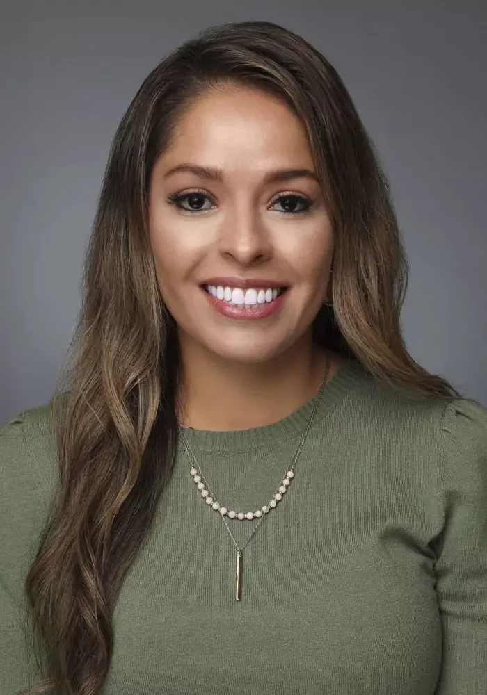 Smiling woman with long hair wearing green top.