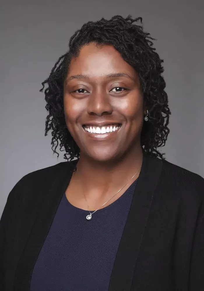 Professional portrait of a smiling woman with curly hair in business attire.
