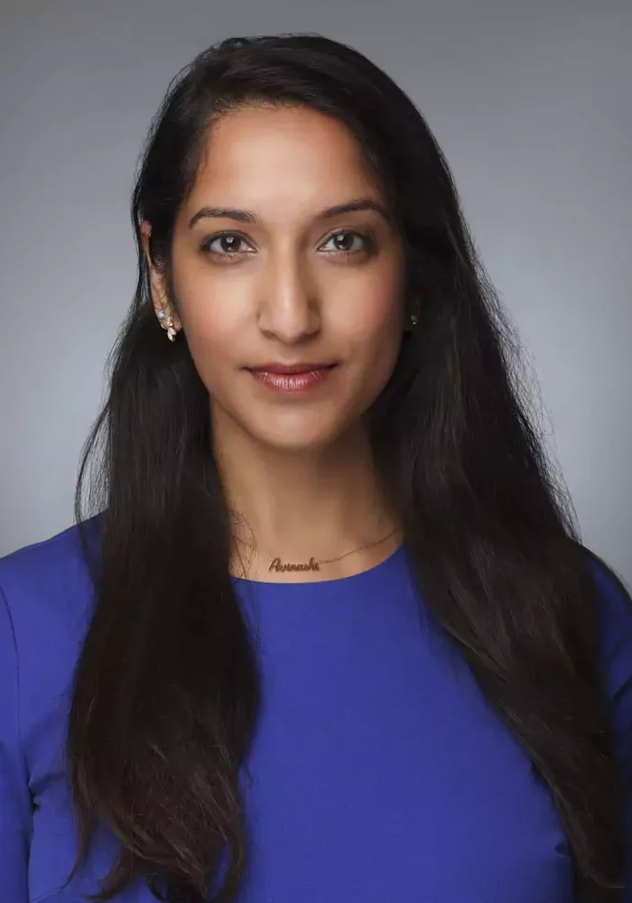 Professional woman with long dark hair wearing a blue top.
