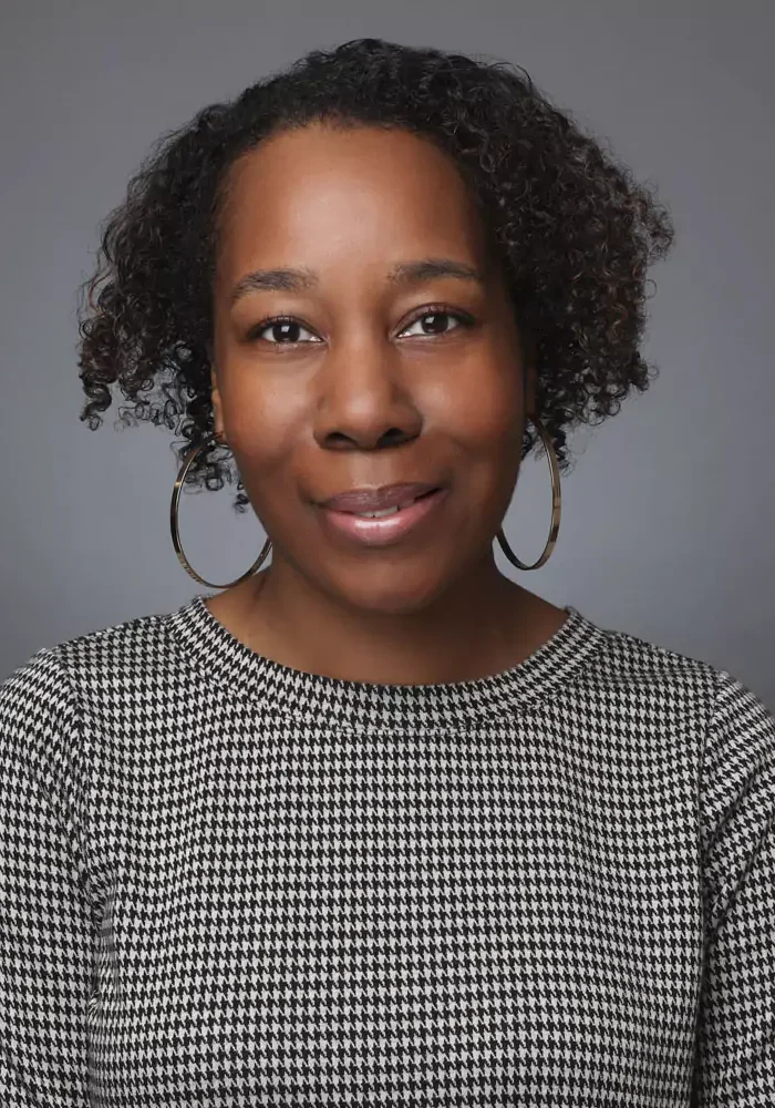 Portrait of a woman with hoop earrings and curly hair.