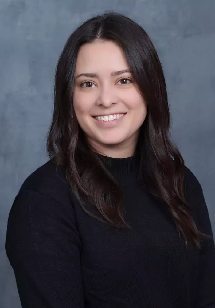 Smiling woman with dark hair in a black top against a gray backdrop.