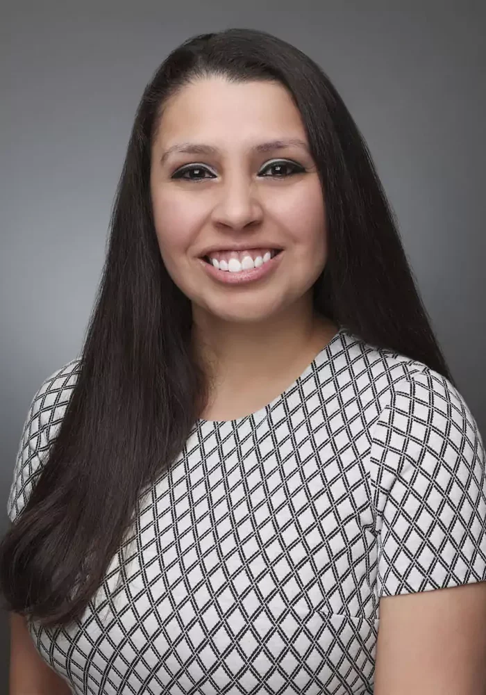 Smiling woman with long dark hair in a patterned top.