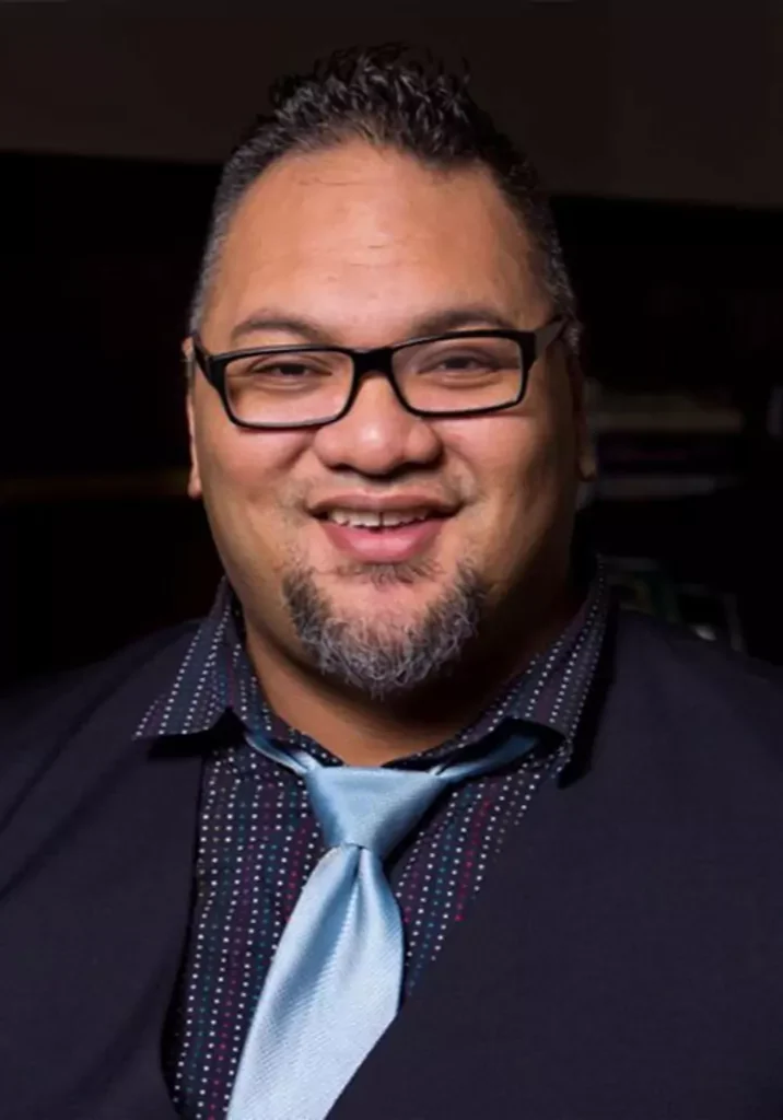 Smiling man with glasses and a blue tie.